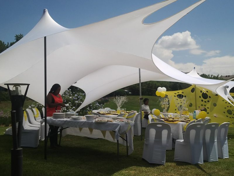 White star tent set up on a green lawn at an outdoor kids party with colourful bunting flags and open garden space in Gauteng